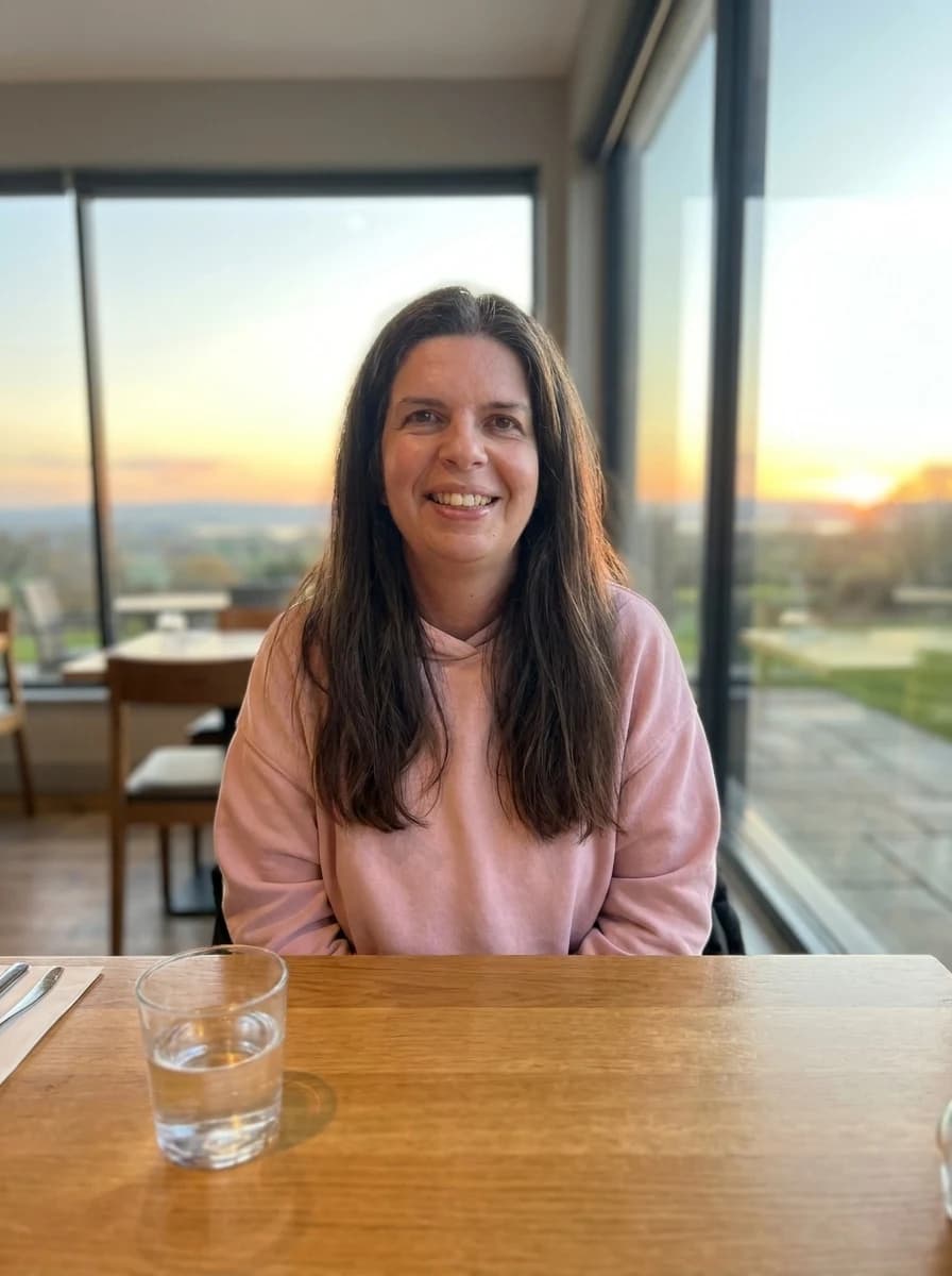 Susan smiling, sitting by a window at golden hour